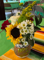 floral arrangement of sunflowers and greenery in a mexican pottery vase